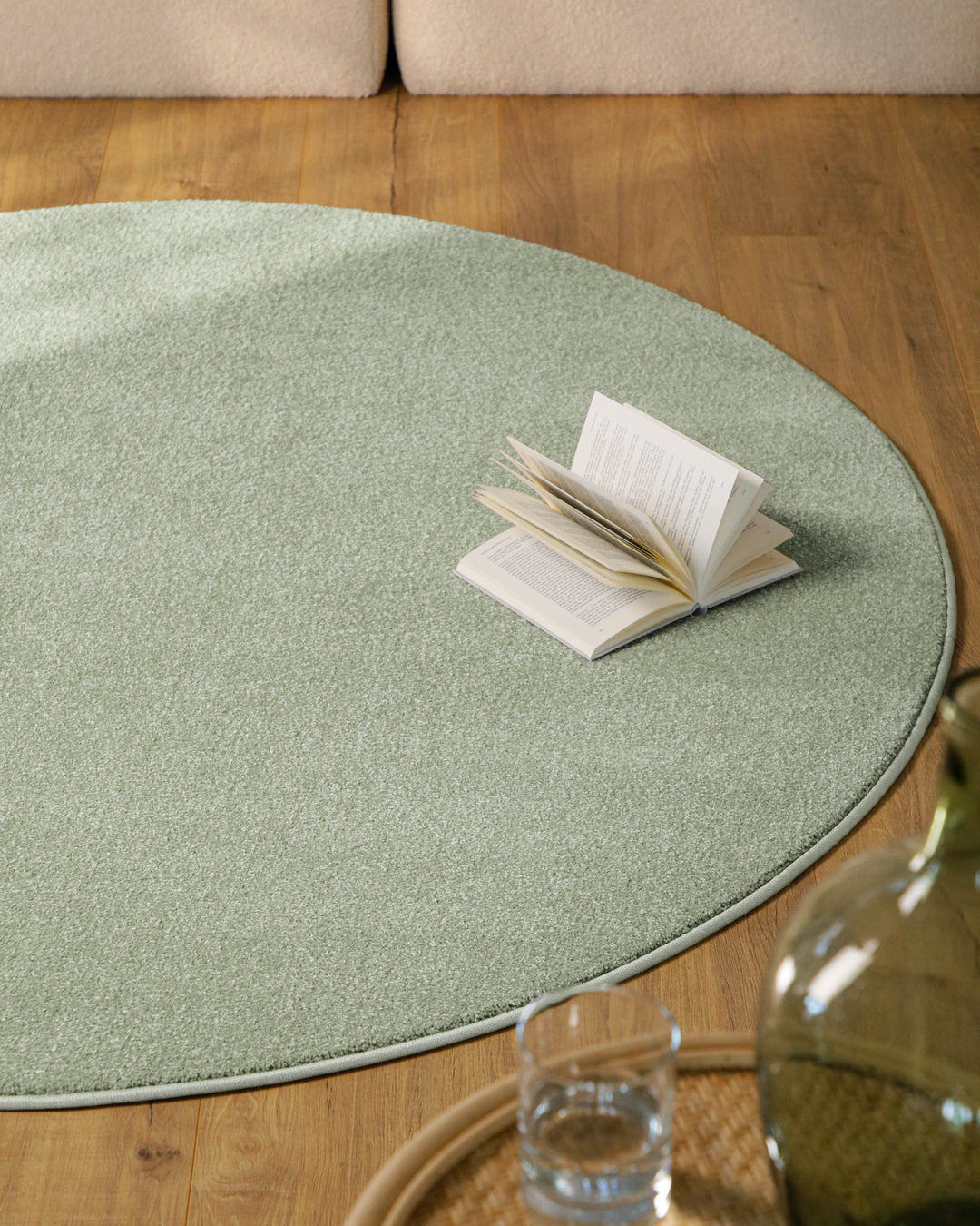 Kurzflor Teppich Vegas Hellgrün rund im Wohnzimmer auf Holzboden vor Sofa, gleichmäßige Oberfläche sichtbar