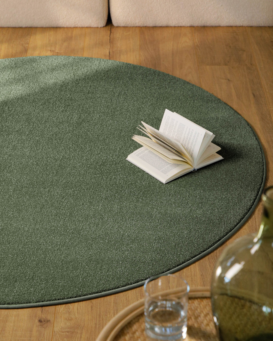 Kurzflor Teppich Vegas Grün rund im Wohnzimmer auf Holzboden, Fläche vor Sofa mit gleichmäßiger Oberfläche