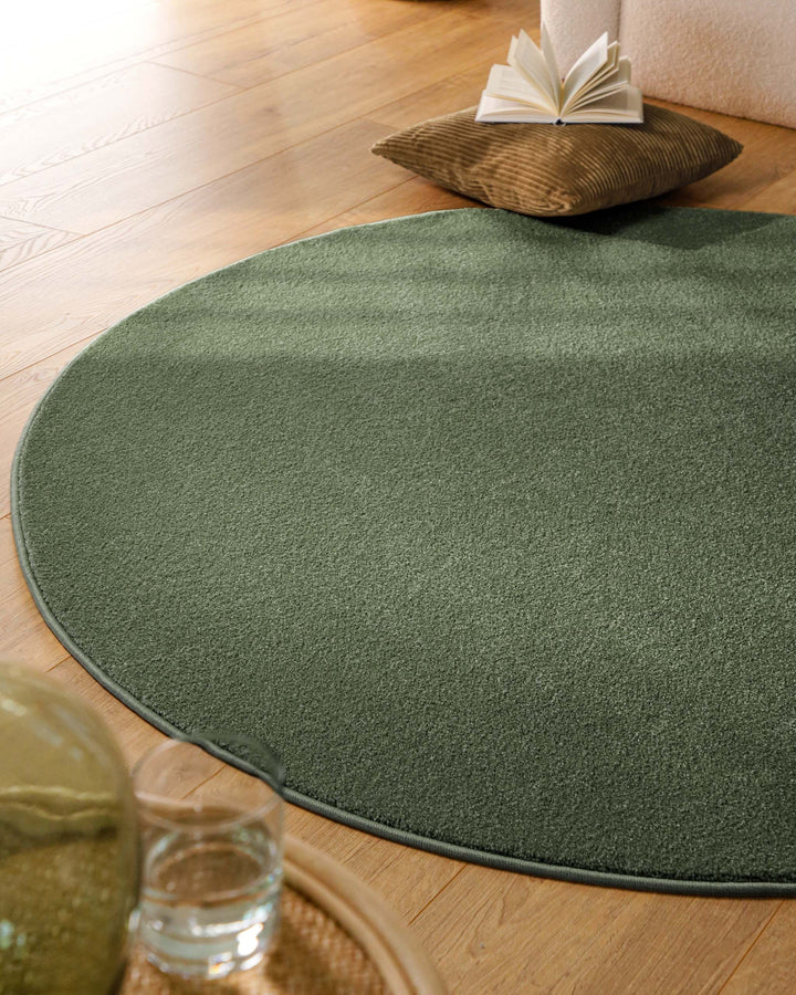 Kurzflor Teppich Vegas Grün rund im Wohnzimmer aus schräger Perspektive, Licht fällt über die Oberfläche