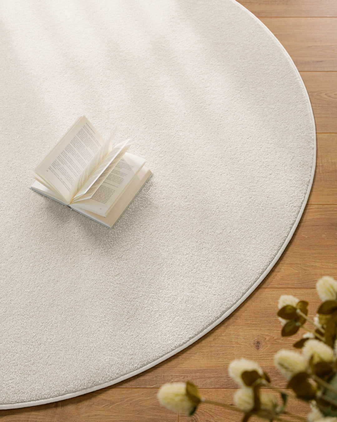Kurzflor Teppich Vegas Creme rund Nahaufnahme mit Buch auf der Oberfläche, feine Struktur des Kurzflors sichtbar