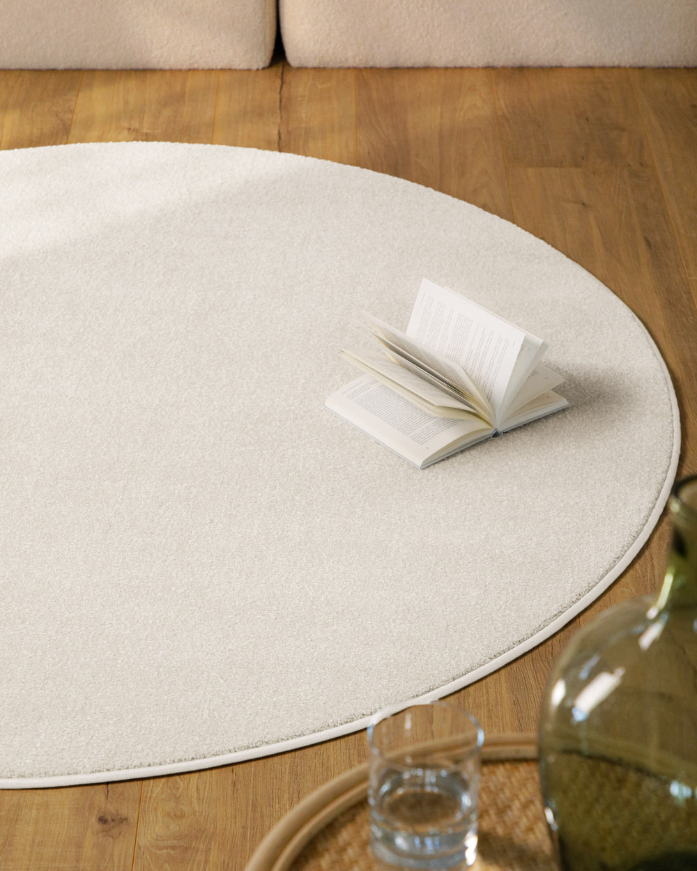 Kurzflor Teppich Vegas Creme rund im Wohnzimmer auf Holzboden vor Sofa, gleichmäßige helle Oberfläche sichtbar