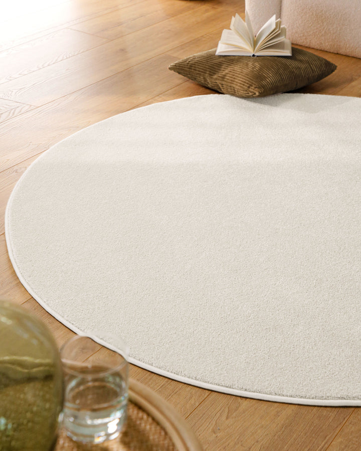 Kurzflor Teppich Vegas Creme rund im Wohnraum aus schräger Perspektive, Licht fällt über die Oberfläche