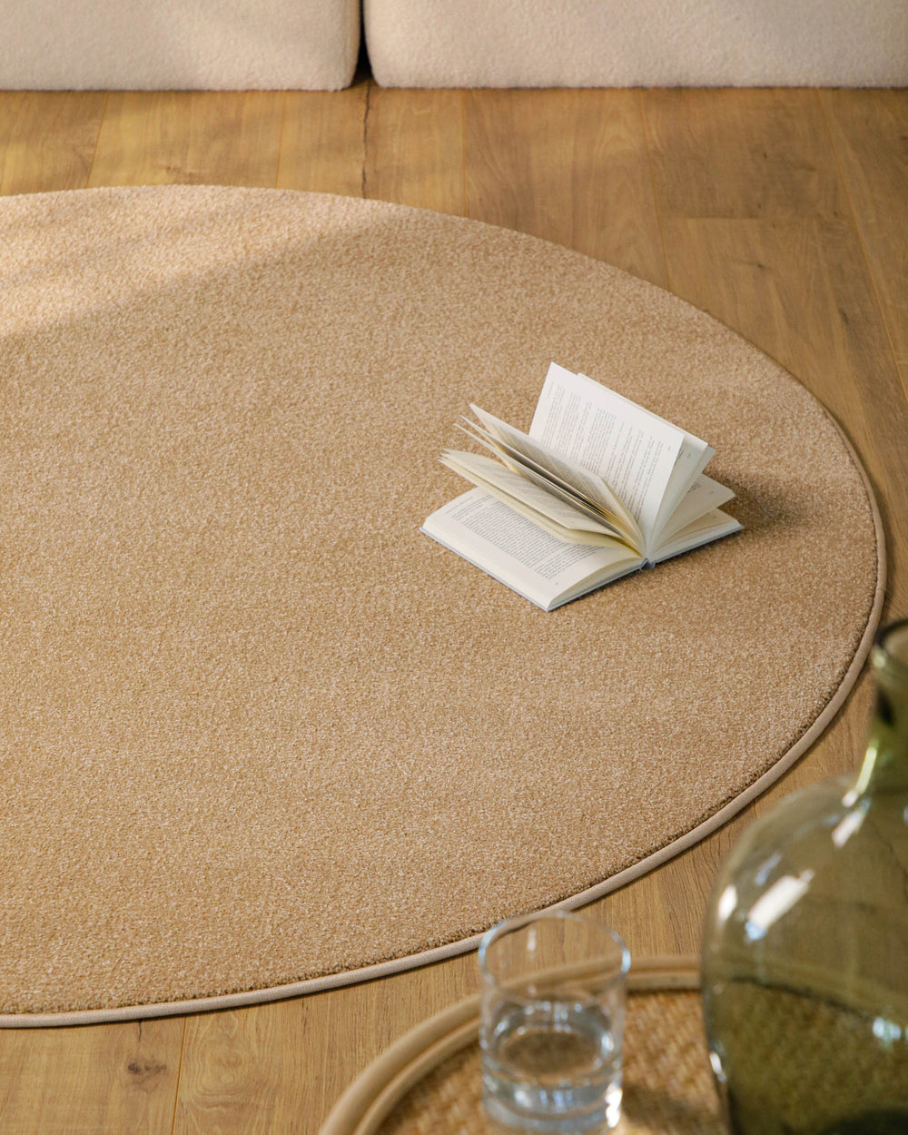 Kurzflor Teppich Vegas Beige rund im Wohnzimmer vor Sofa auf Holzboden, warme natürliche Farbwirkung