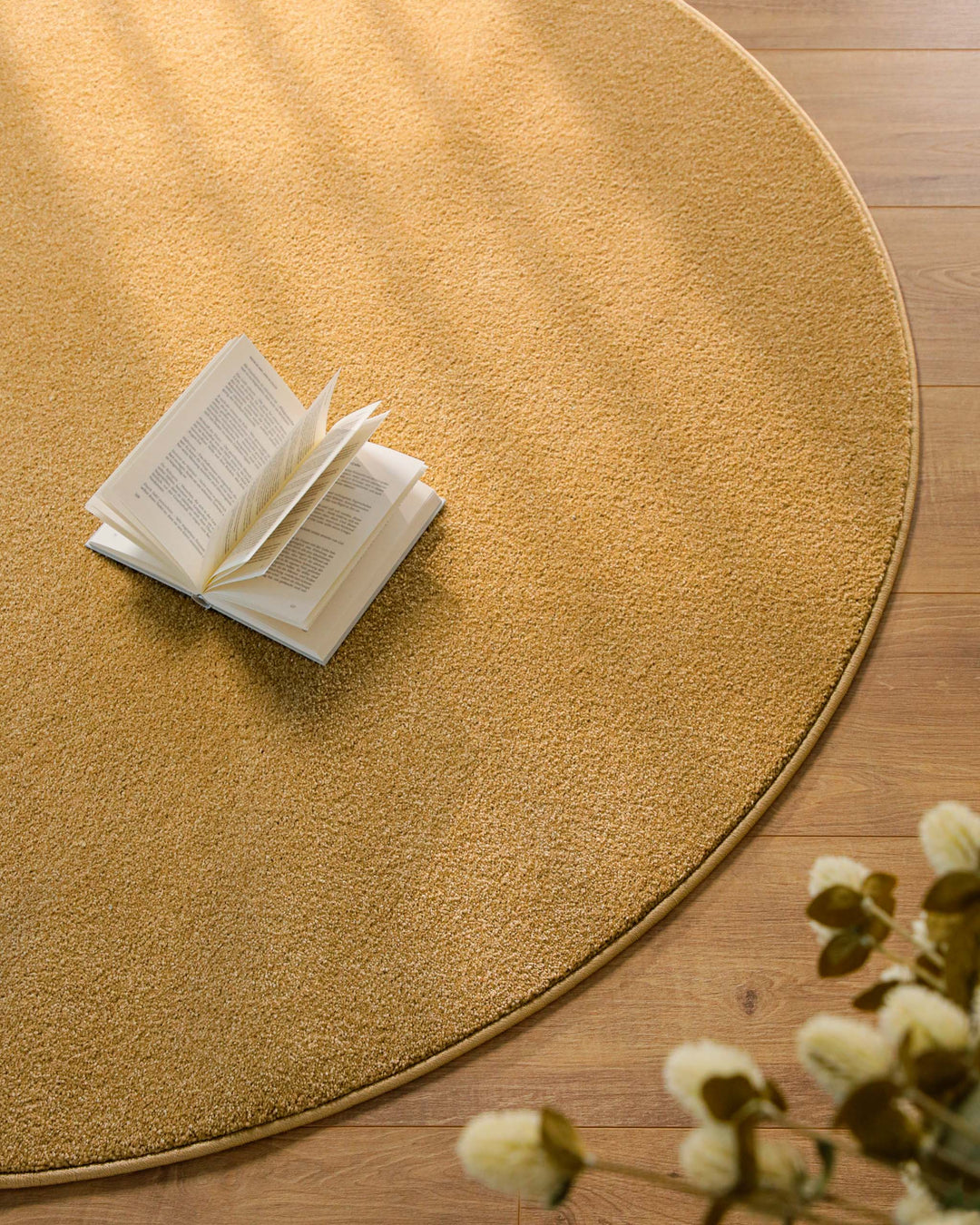 Kurzflor Teppich Vegas Ocker Gelb rund Detailaufnahme mit Buch auf der Oberfläche