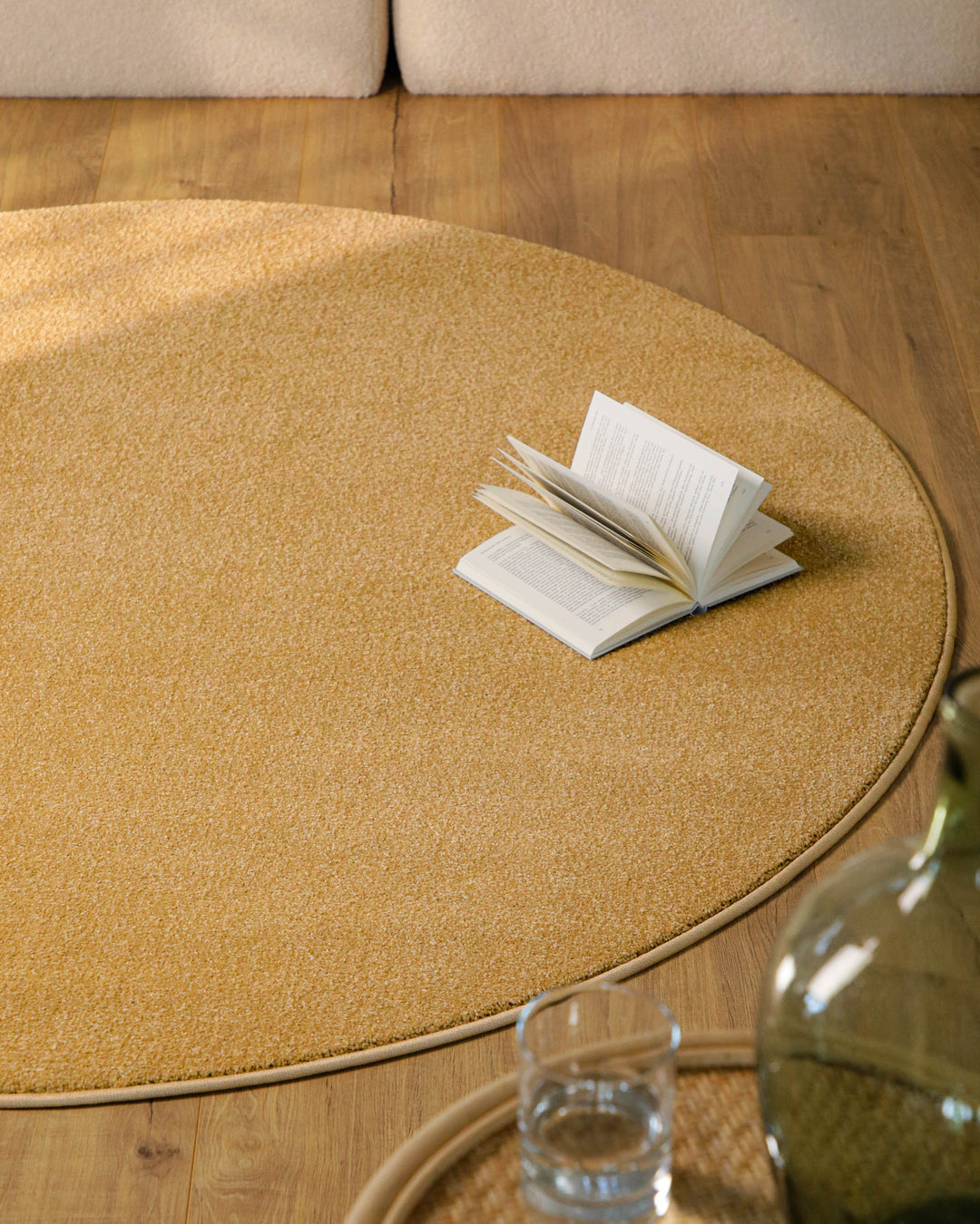 Kurzflor Teppich Vegas Ocker Gelb rund im Wohnzimmer vor Sofa auf Holzboden, warme Farbwirkung