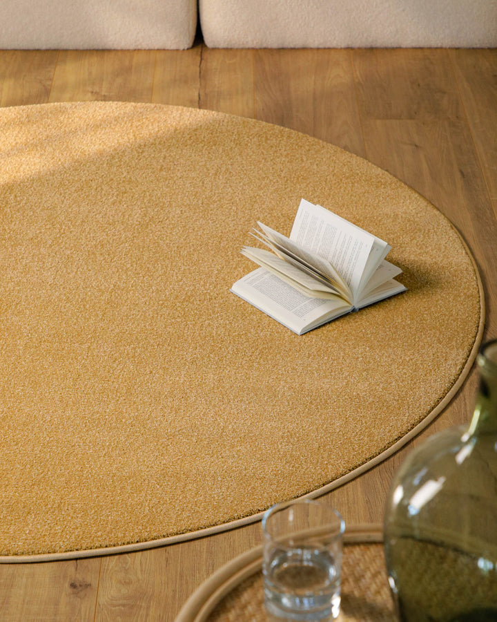 Kurzflor Teppich Vegas Ocker Gelb rund im Wohnzimmer vor Sofa auf Holzboden, warme Farbwirkung