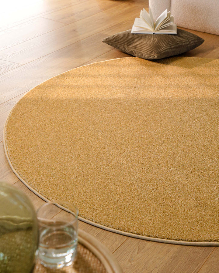 Kurzflor Teppich Vegas Ocker Gelb rund im Wohnraum aus schräger Perspektive mit natürlichem Lichteinfall