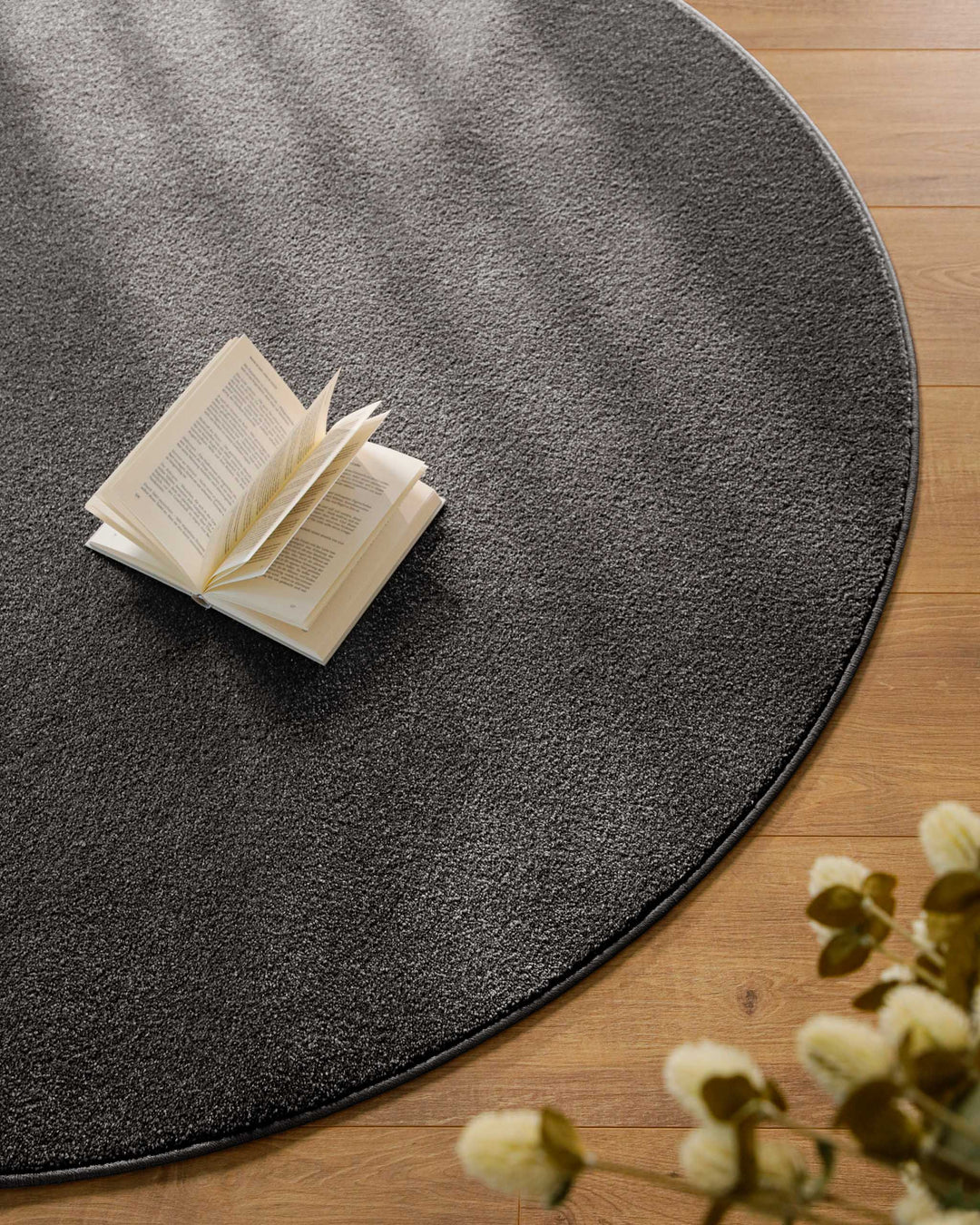 Kurzflor Teppich Vegas Anthrazit rund Detailaufnahme mit Buch auf der Oberfläche