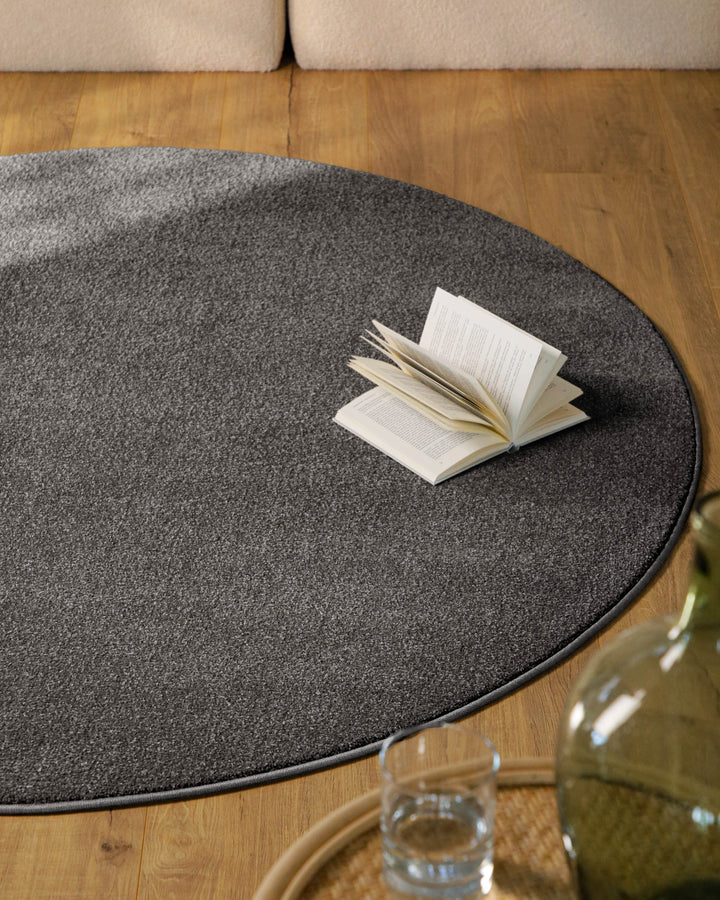 Kurzflor Teppich Vegas Anthrazit rund im Wohnzimmer vor Sofa auf Holzboden, moderner Kontrast