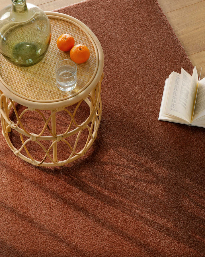 Kurzflor Teppich Vegas Rot Nahaufnahme mit Beistelltisch und Buch, feine Florstruktur im Wohnumfeld