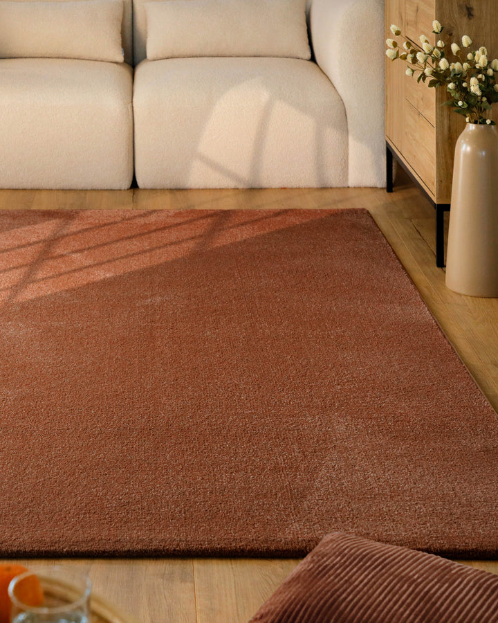Kurzflor Teppich Vegas Rot im Wohnzimmer vor Sofa auf Holzboden, gleichmäßige Oberfläche mit warmem Farbton
