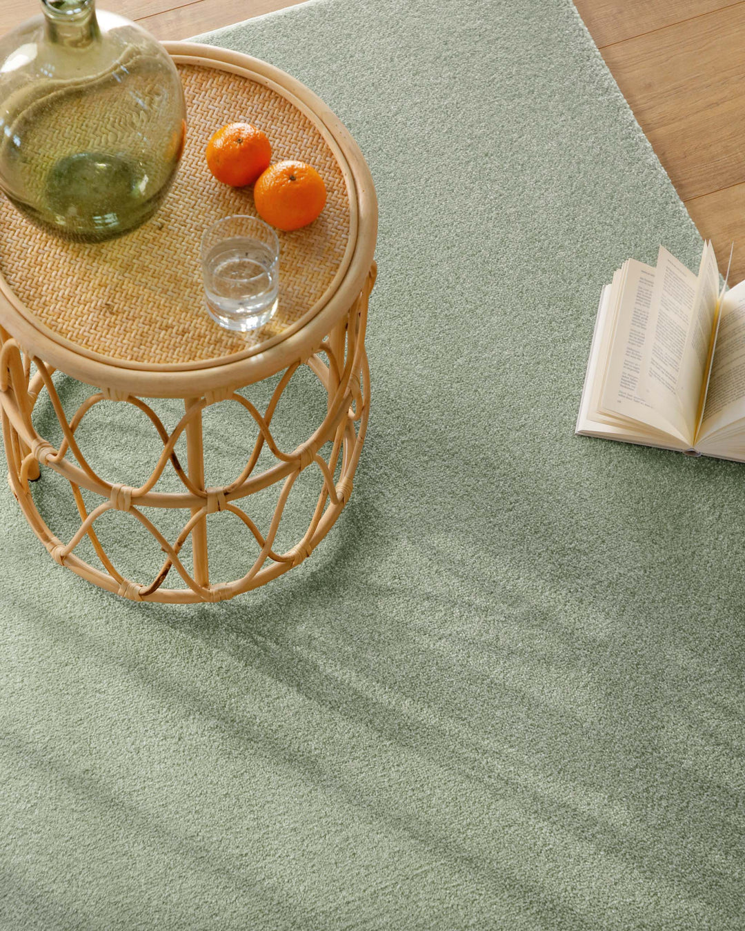 Kurzflor Teppich Vegas Hellgrün Nahaufnahme mit Beistelltisch und Buch auf der Oberfläche, feine Struktur erkennbar