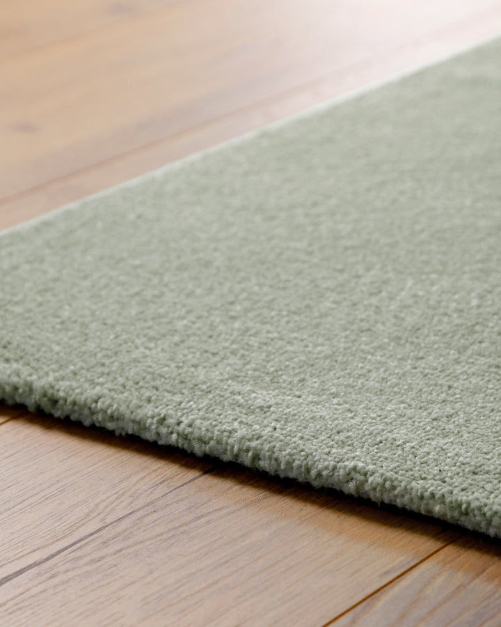 Kurzflor Teppich Vegas Hellgrün Detail der Teppichkante auf Holzboden, flacher Abschluss und gleichmäßige Struktur