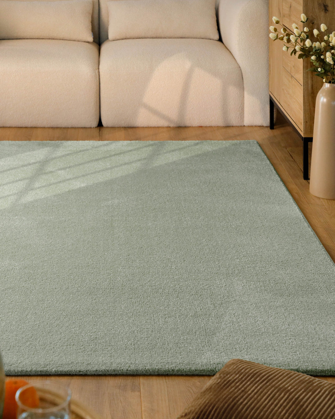 Kurzflor Teppich Vegas Hellgrün im Wohnzimmer vor Sofa auf Holzboden, gleichmäßige Oberfläche mit hellem Farbton