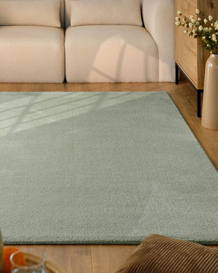 Kurzflor Teppich Vegas Hellgrün im Wohnzimmer vor Sofa auf Holzboden, gleichmäßige Oberfläche mit hellem Farbton