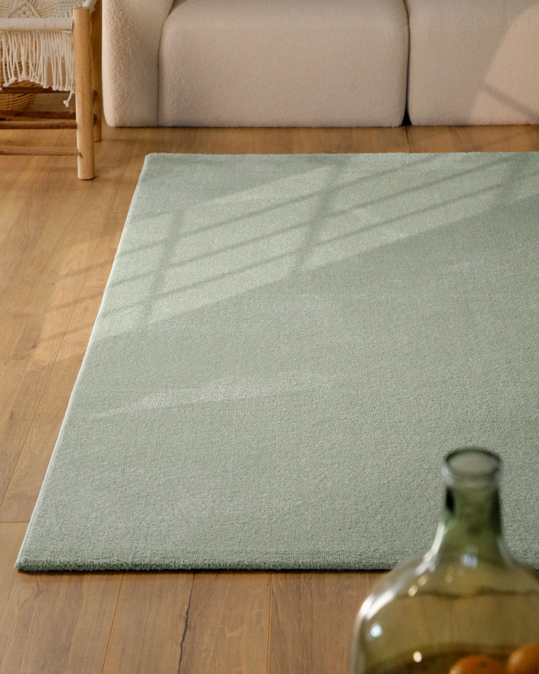 Kurzflor Teppich Vegas Hellgrün im Wohnzimmer aus schräger Perspektive, Licht fällt über die Oberfläche