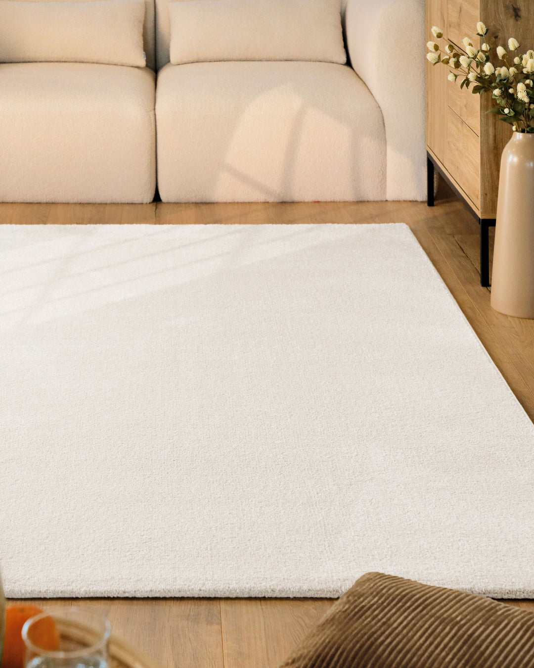 Kurzflor Teppich Vegas Creme im Wohnzimmer vor Sofa auf Holzboden, gleichmäßige helle Oberfläche sichtbar
