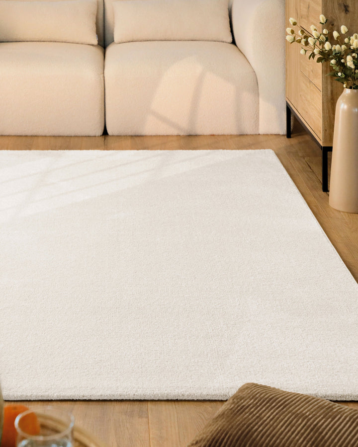 Kurzflor Teppich Vegas Creme im Wohnzimmer vor Sofa auf Holzboden, gleichmäßige helle Oberfläche sichtbar