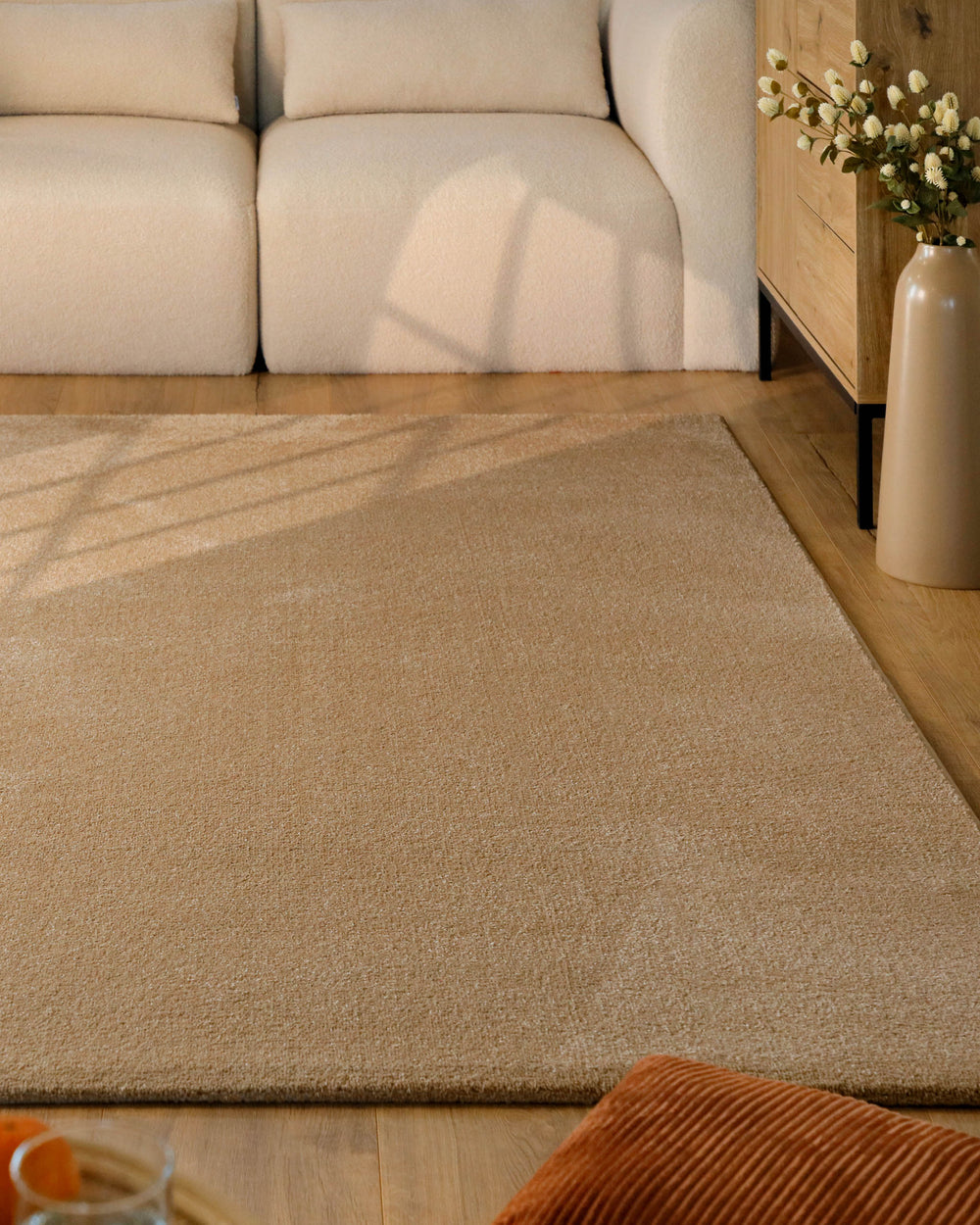 Kurzflor Teppich Vegas Beige im Wohnzimmer vor Sofa auf Holzboden, warme natürliche Farbwirkung