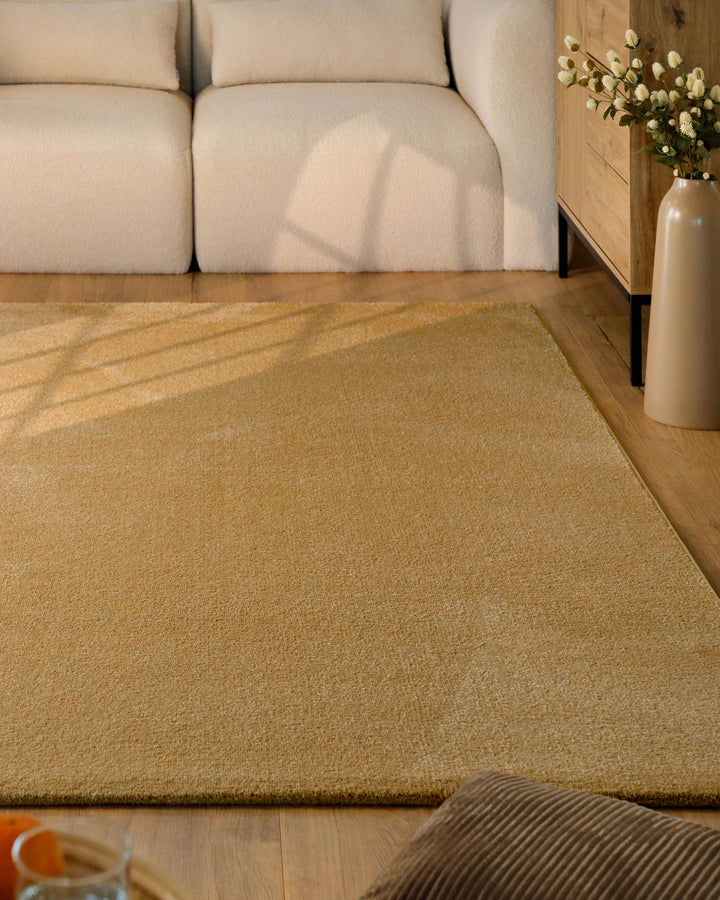 Kurzflor Teppich Vegas Ocker Gelb im Wohnzimmer vor Sofa, warme Farbwirkung auf Holzboden