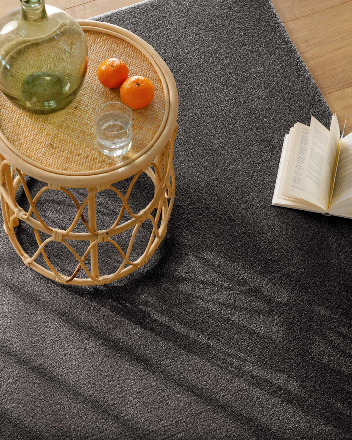 Kurzflor Teppich Vegas Anthrazit Detailaufnahme mit Tisch und Deko, Licht fällt über die Oberfläche