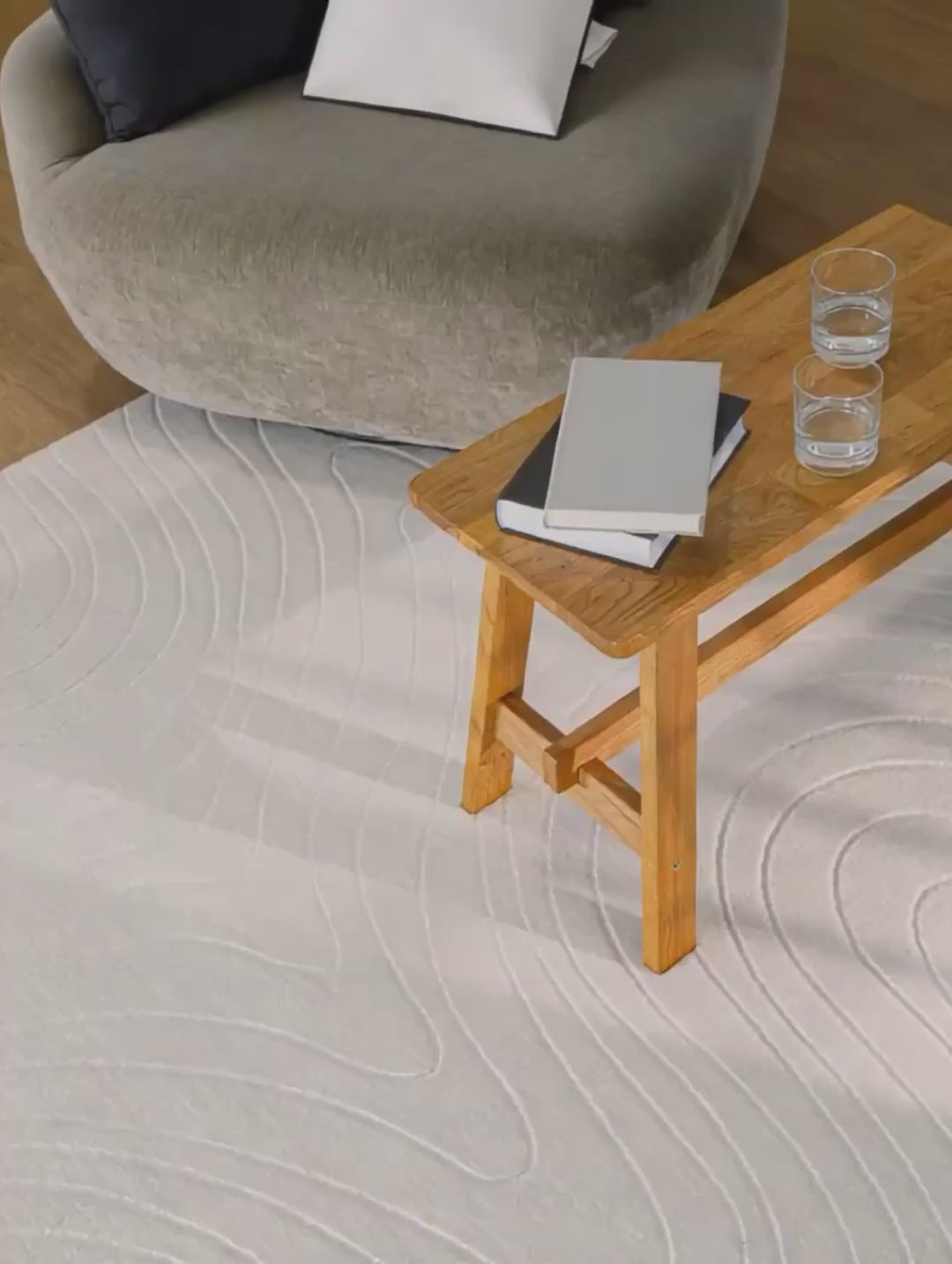 Nuuk Flow Kurzflorteppich Produtvideo creme-weiß im hellen Wohnzimmer mit Holztisch und Sessel